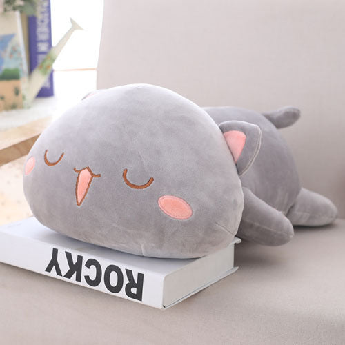 Gray plush cat-shaped pillow on a book with a light background