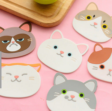 Cat-shaped coasters with various facial expressions on a pink background
