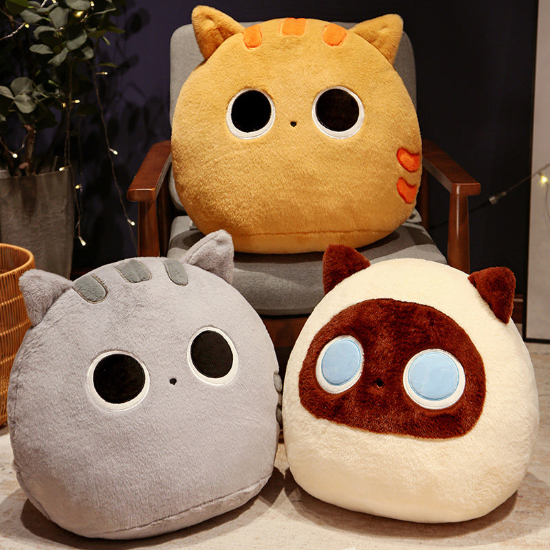 Three cat-shaped cushions in different colors sitting on a chair.