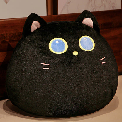 Black cat-shaped plush toy with large blue eyes on a wooden surface.