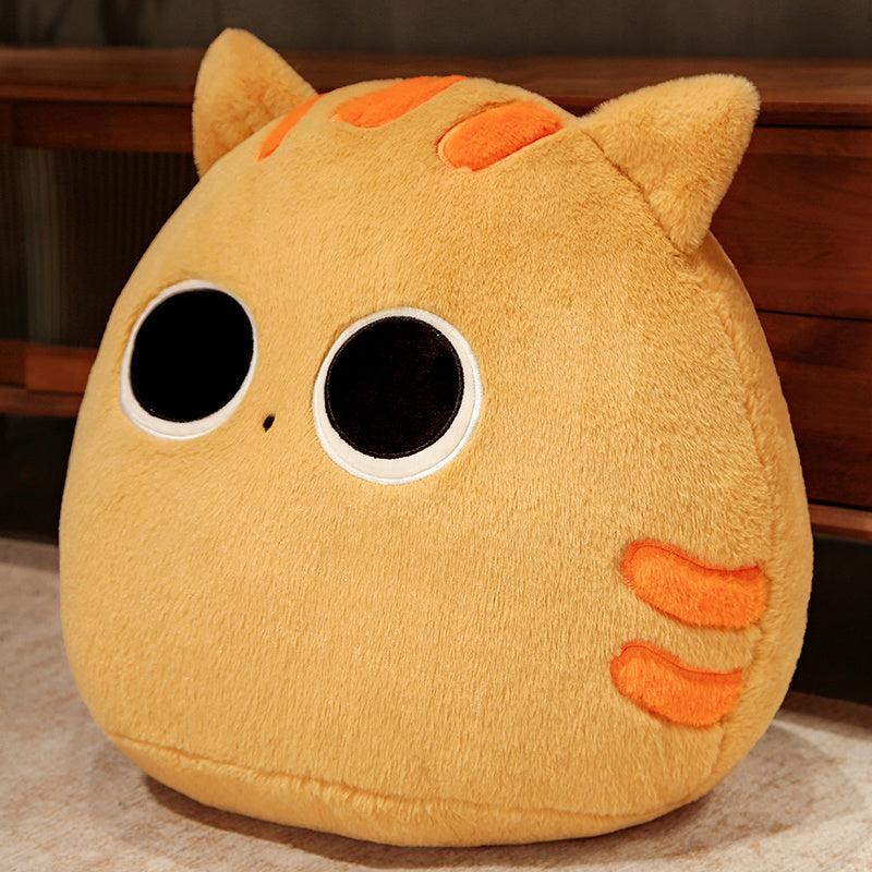 Plush toy resembling a cat with orange accents on a wooden surface