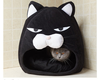 Black cat-shaped pet bed with a cat peeking out from inside, against a tiled wall background.