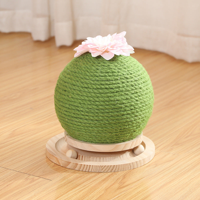 Green scratching ball with a white flower on a wooden surface with wooden balls