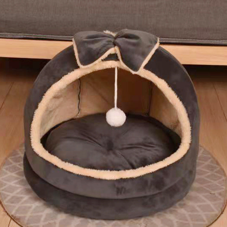 Cat bed with a bow and ball on top, placed on a wooden floor - Neferpaws