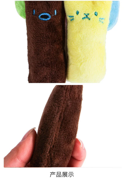 Close-up of a brown plush toy with green ears and blue text, held by a hand.