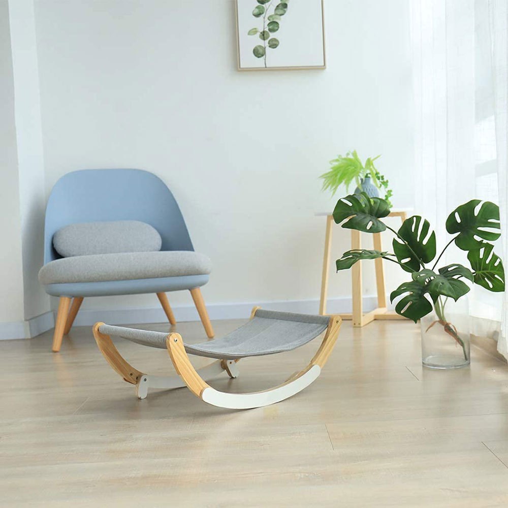 Modern rocking chair in a minimalistic room with plants and a side table.