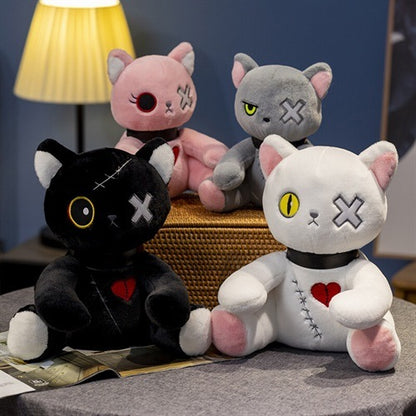 Four plush toys shaped like cats with various designs on a surface.
