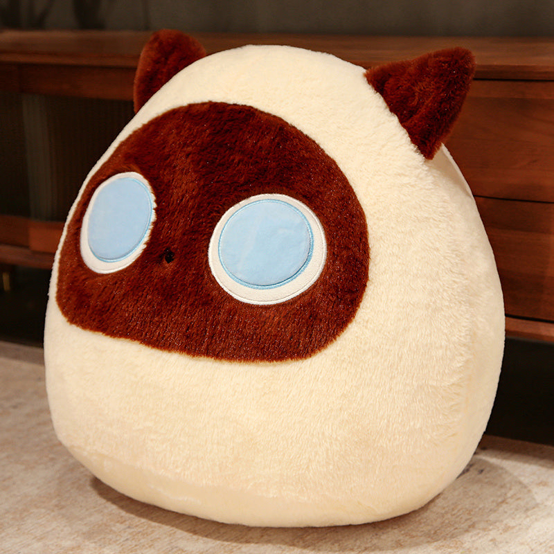 Plush toy with a round face, brown ears, and blue eyes on a wooden surface.