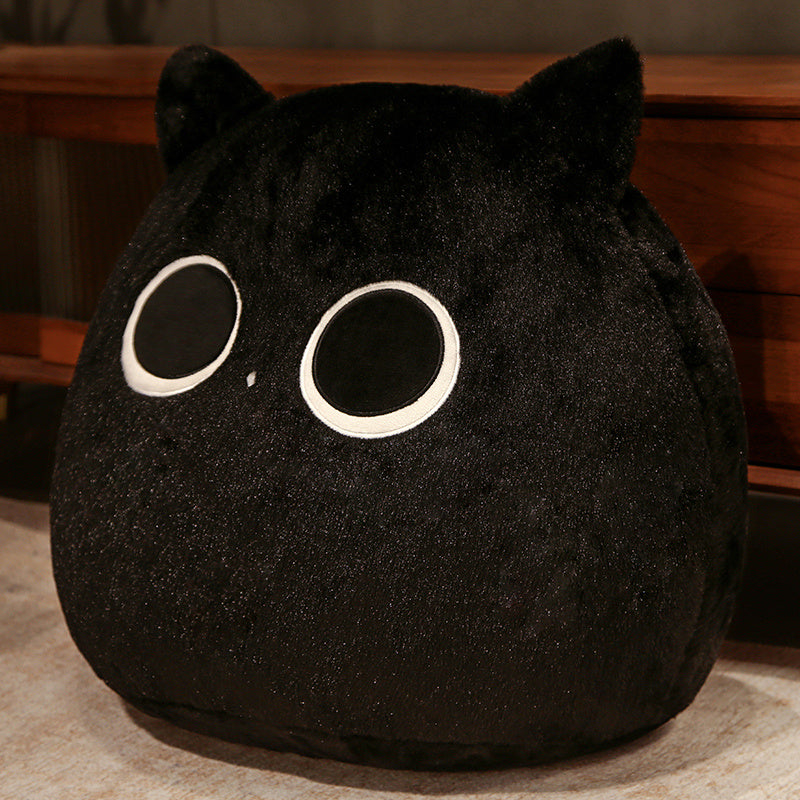 Black plush toy with large eyes on a wooden surface